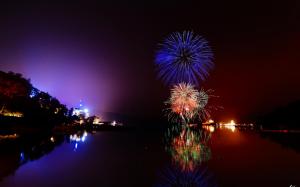 Colorful Fireworks Above A River In Pitch Black wallpaper thumb